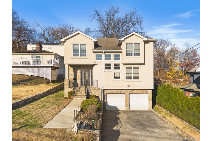 Traditional-style home with stone siding, stucco siding, asphalt driveway, and a garage