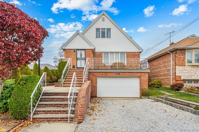 View of front of house with stairway, brick siding, a balcony, and driveway