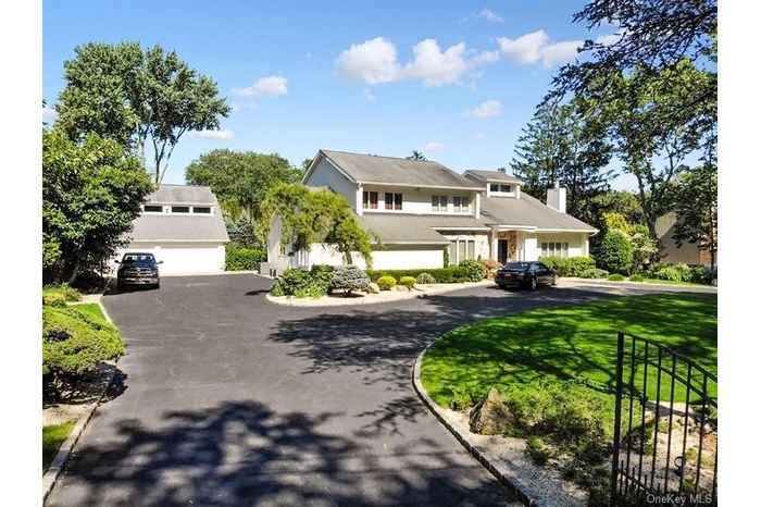 View of front of home with a front yard, a chimney, and curved driveway