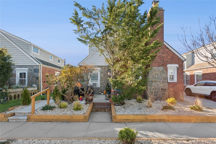 View of front of home featuring a chimney, stone siding, and brick siding