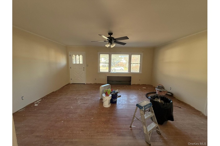 Unfurnished living room with crown molding, a ceiling fan, and wood finished floors
