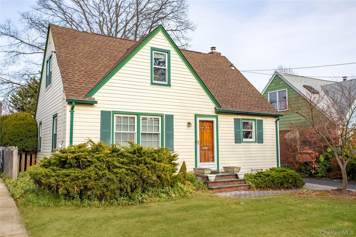 View of front facade with roof with shingles and a chimney