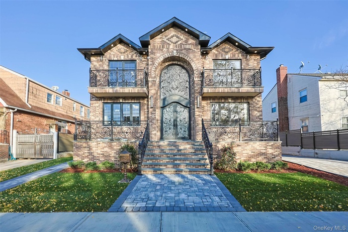 View of front of property featuring brick siding, a balcony, and french doors