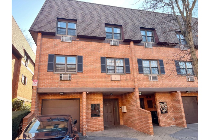 View of front of house with brick siding, a garage, a shingled roof, and driveway