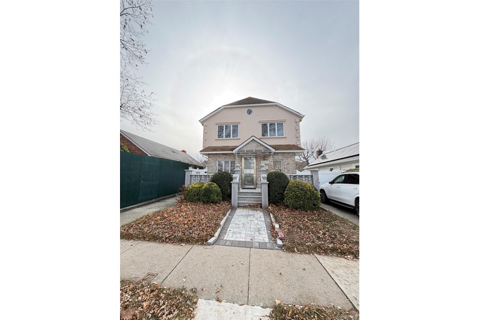 View of front of property with a fenced front yard, stucco siding, and stone siding