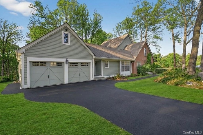 Traditional-style home with driveway, a front yard, and a garage