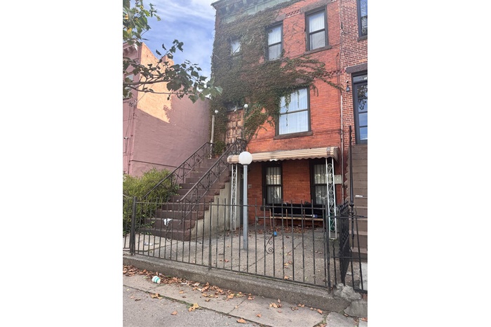 View of front of house featuring a fenced front yard, brick siding, and stairs