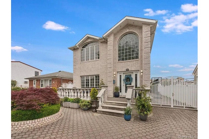 Traditional-style house with a gate, brick siding, and a patio area