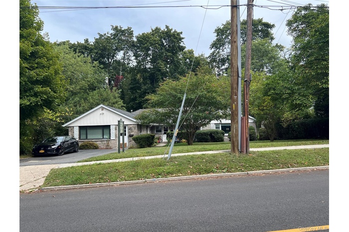 View of front of house with a front lawn, driveway, and stone siding