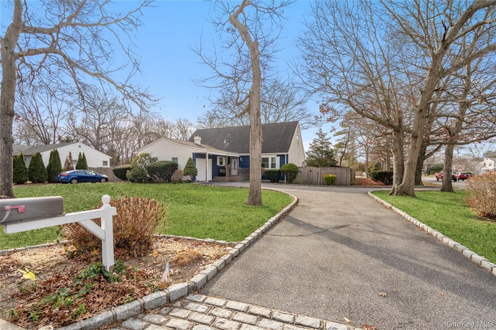 View of front facade featuring asphalt driveway, covered porch, and a chimney