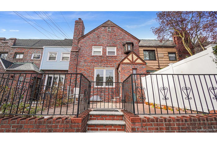 Tudor home with a fenced front yard, brick siding, a chimney, and a gate