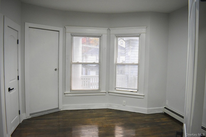 Spare room with baseboard heating and dark wood-style floors