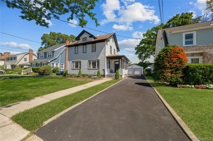 View of front of house featuring an outbuilding, a front lawn, and a detached garage