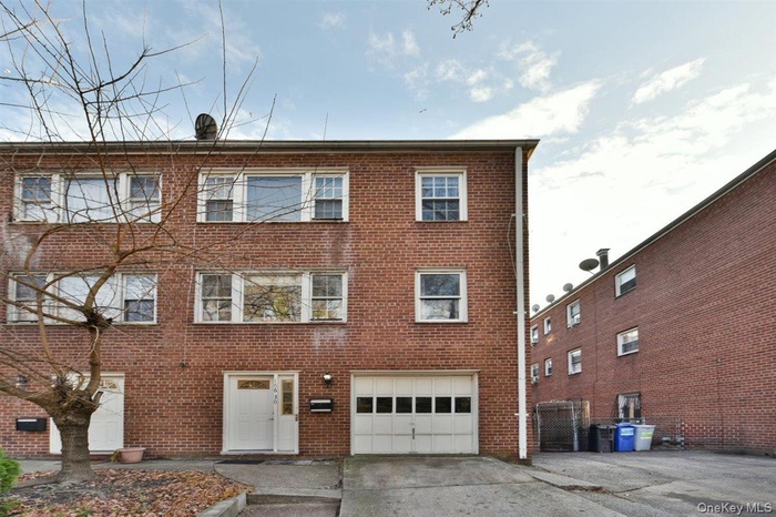 Back of property with brick siding, concrete driveway, and an attached garage