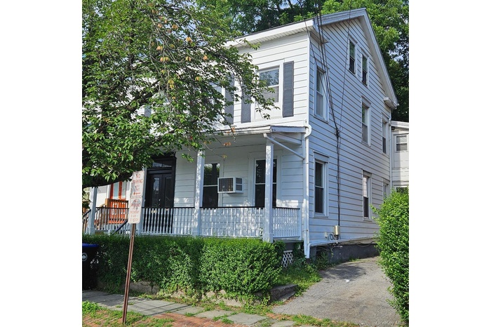 View of front of property with a porch and a wall mounted AC