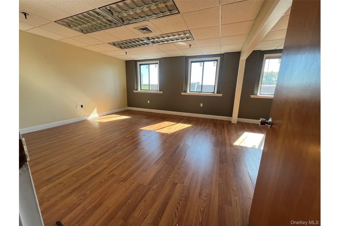 Empty room featuring wood finished floors and a paneled ceiling