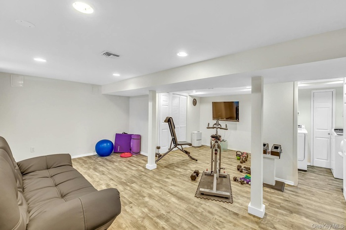 Workout area with light wood-type flooring, washer / dryer, and recessed lighting