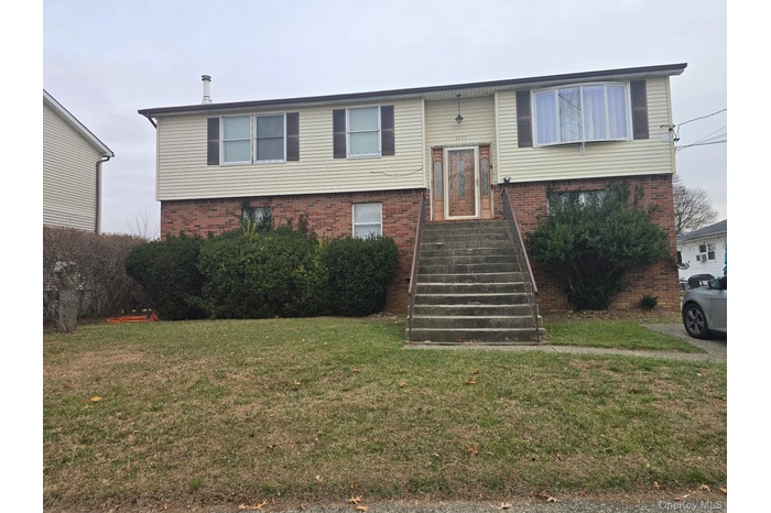 Split foyer home featuring brick siding and a front lawn