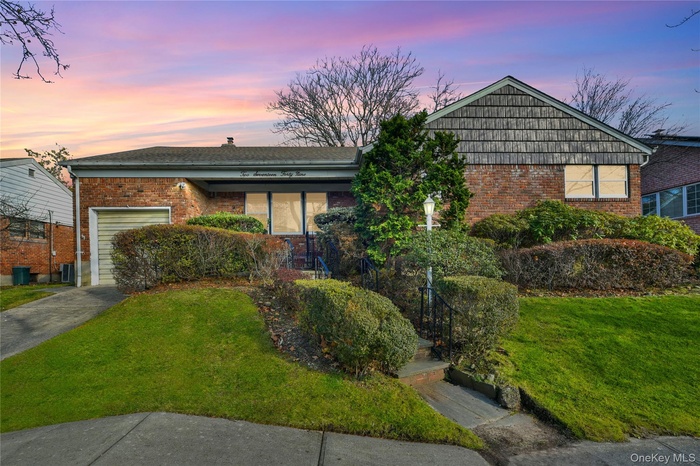 Single story home with a front yard, brick siding, a garage, and driveway