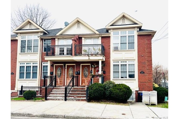 View of front of property with a balcony and brick siding