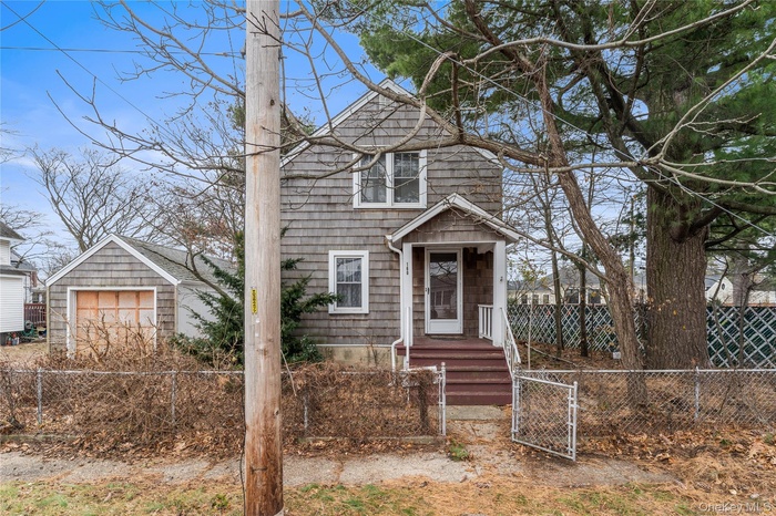 View of front of house with a fenced front yard, a gate, and a detached garage