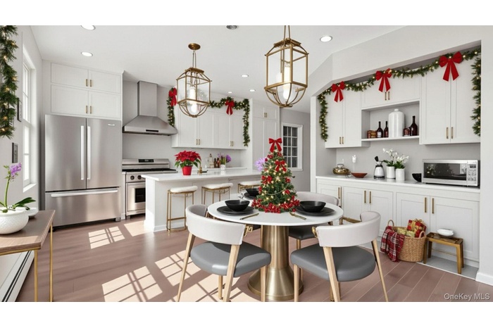 Kitchen featuring appliances with stainless steel finishes, wall chimney exhaust hood, pendant lighting, light countertops, and white cabinetry