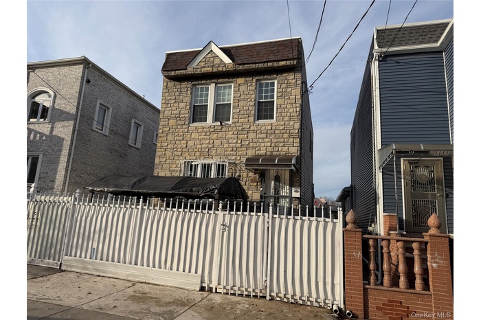 View of front of property featuring stone siding, a gate, and a fenced front yard