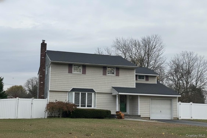 View of front of property with a gate, a chimney, a garage, driveway, and roof with shingles