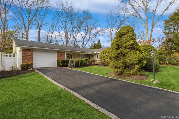 A ranch-style home featuring a garage, a driveway, and a mix of brick and siding.