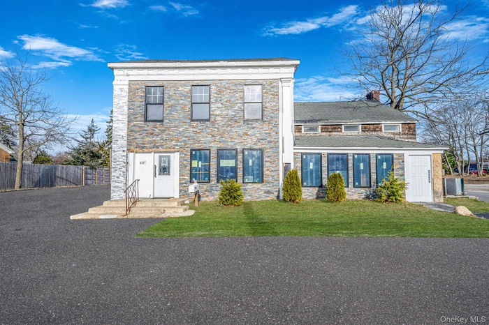 View of front facade featuring a chimney and stone siding