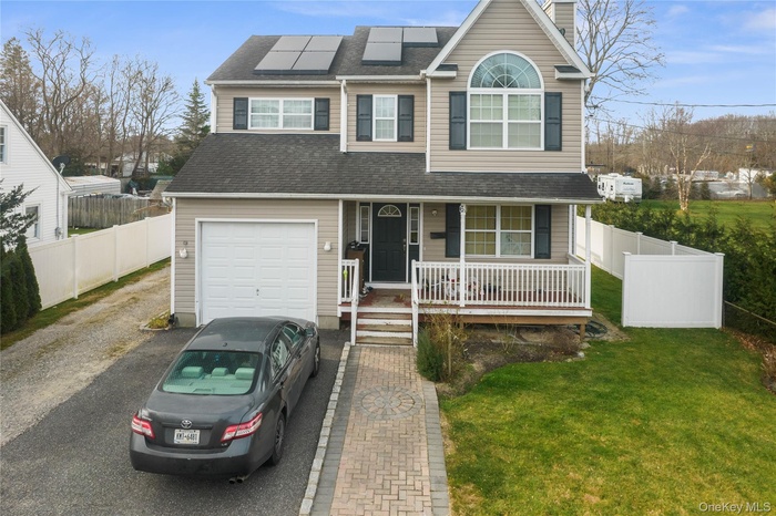 Traditional-style house with covered porch, solar panels, driveway, a chimney, and roof with shingles