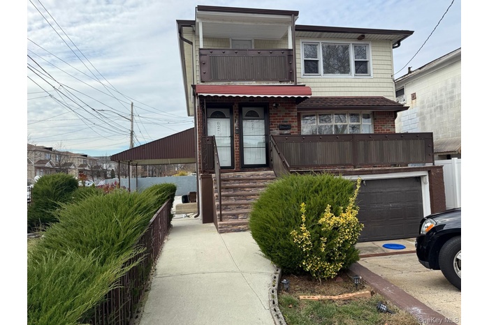 View of front of property featuring a balcony, concrete driveway, stairs, brick siding, and an attached garage