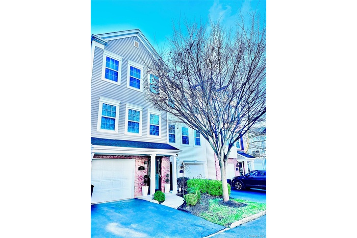 View of front of property featuring a porch, brick siding, asphalt driveway, and an attached garage