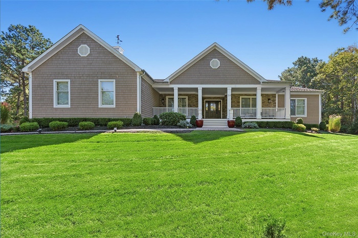 View of front of home with a porch, a front lawn, and a chimney