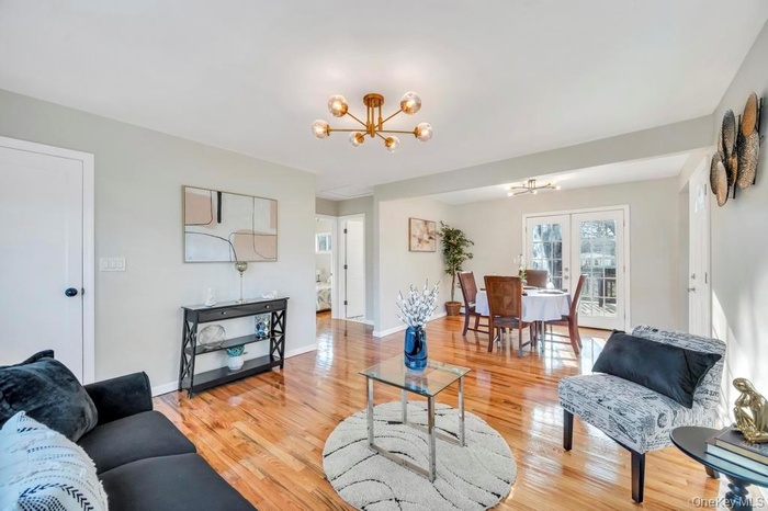 Living area with light wood-style floors, a chandelier, and french doors