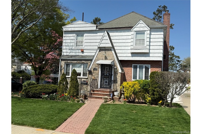 View of front of house with a chimney, a front lawn, and brick siding