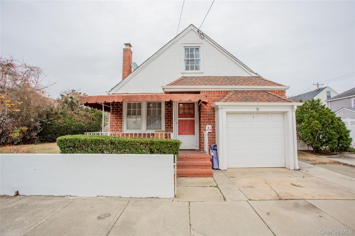 View of front of house with brick siding, concrete driveway, covered porch, and a chimney