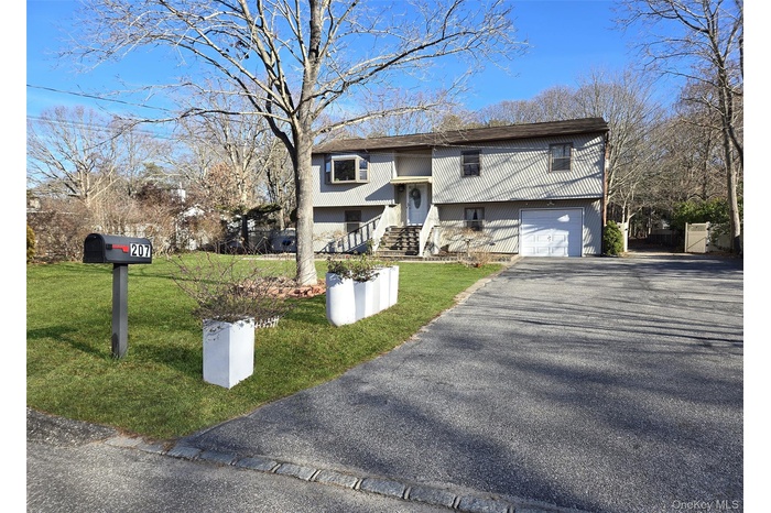 Raised ranch with a front yard, asphalt driveway, and an attached garage