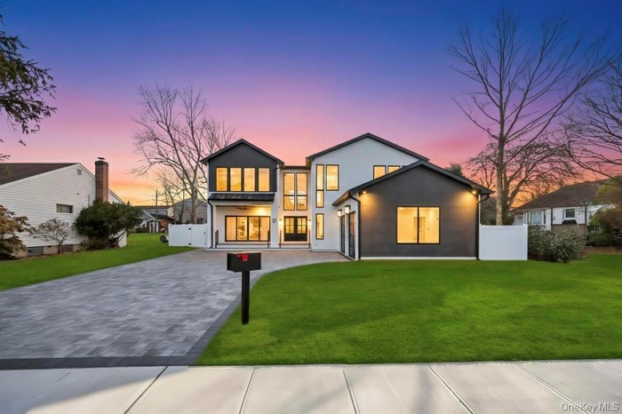 Back of property at dusk featuring decorative driveway and stucco siding