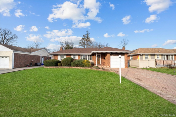 Ranch-style house with a front yard, brick siding, a chimney, driveway, and a garage