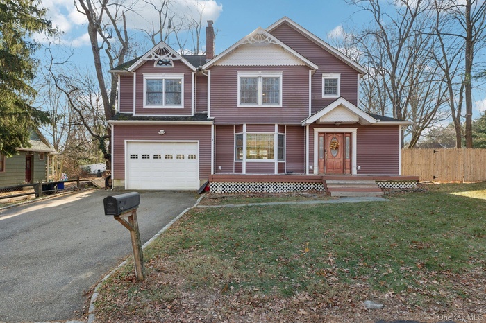 View of front of property with driveway, a chimney, and an attached garage