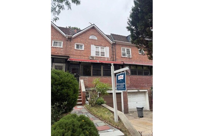 Traditional-style home with brick siding, stairway, an attached garage, and driveway