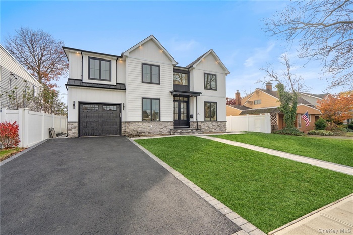 View of front facade with driveway, stone siding, an attached garage, and board and batten siding