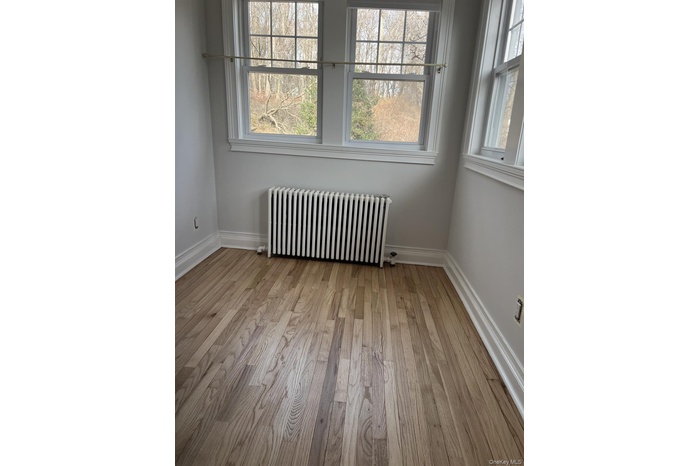 Empty room featuring radiator heating unit and light wood finished floors
