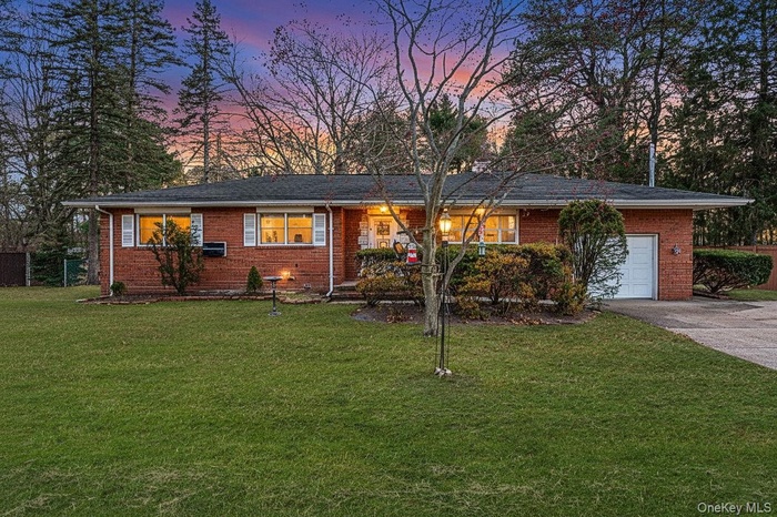 Ranch-style house with a lawn, brick siding, driveway, and an attached garage