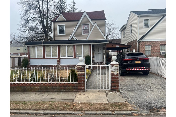 View of front of property featuring a gate, a fenced front yard, brick siding, and covered porch