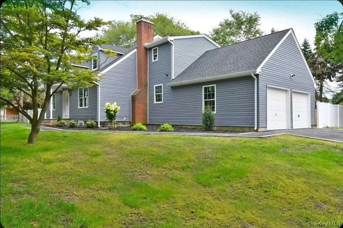 View of front of home featuring a garage, a chimney, a shingled roof, and asphalt driveway