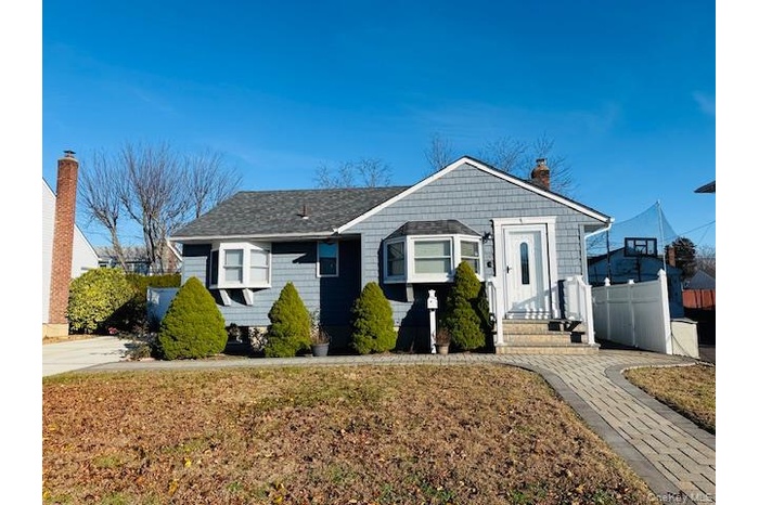 View of front facade with a chimney and roof with shingles