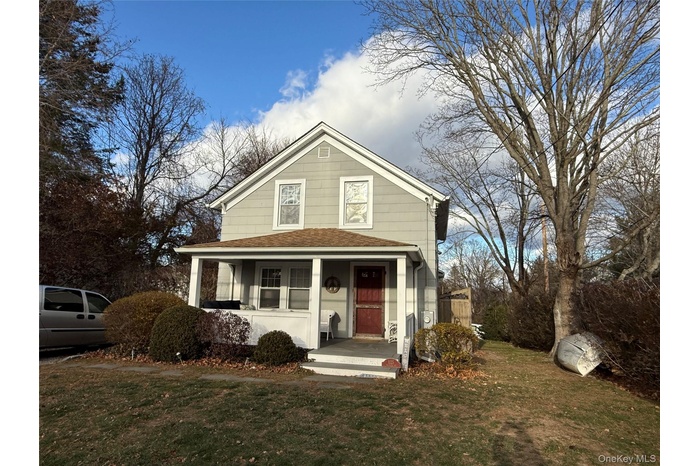 View of front of property featuring a shingled roof, a front lawn, and covered porch
