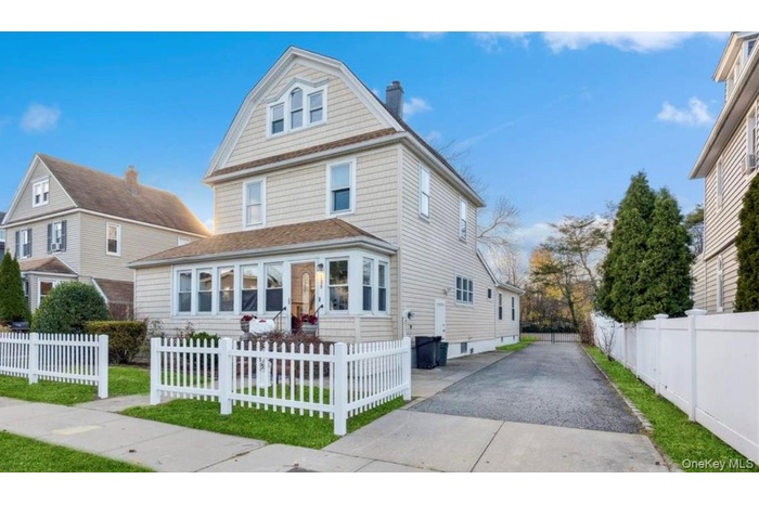 Traditional style home featuring a fenced front yard, a chimney, and driveway